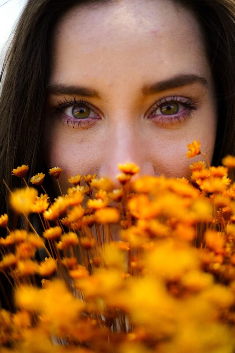 woman half face behind orange flowers