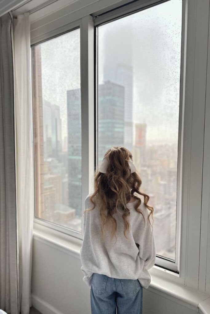 curly haired woman looking out window