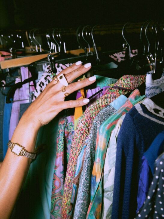close up on hand looking at clothes on rail in charity shop