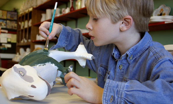 boy painting pottery at paint thr town cafe