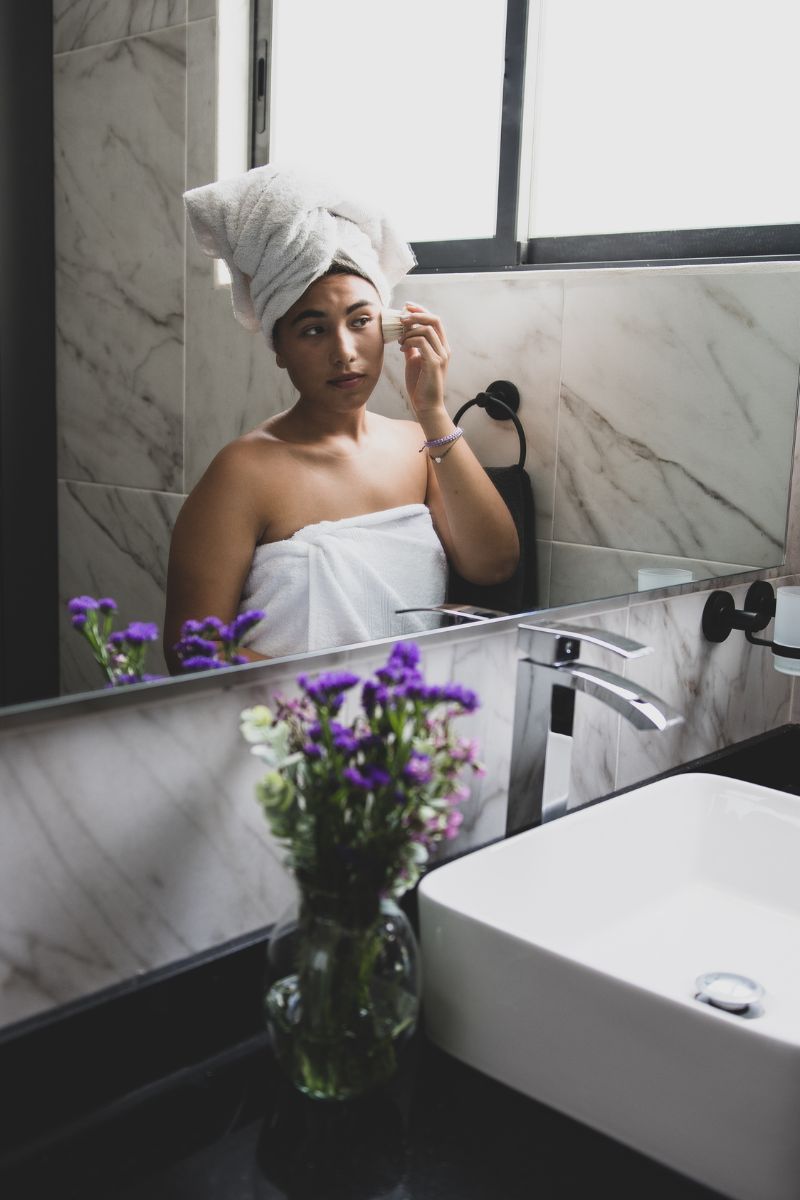 woman doing skincare in front of mirror
