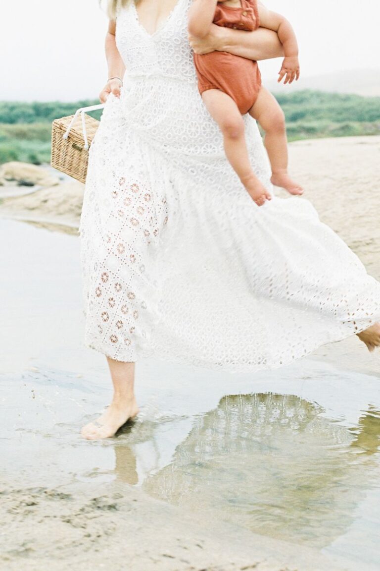 woman holding baby walking thru sea