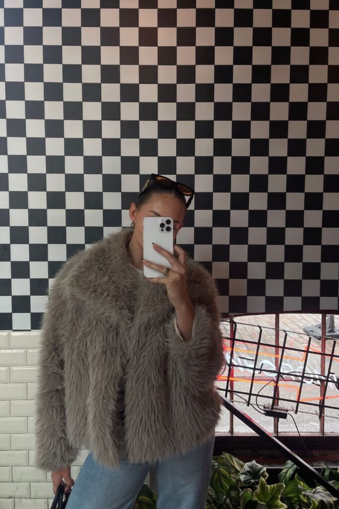 woman standing in front of check wall taking selfie