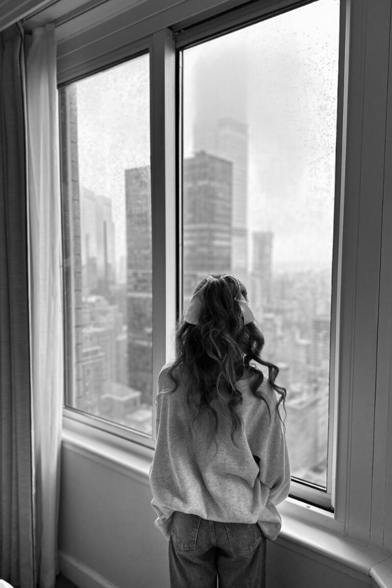 woman staring out window with herback to us