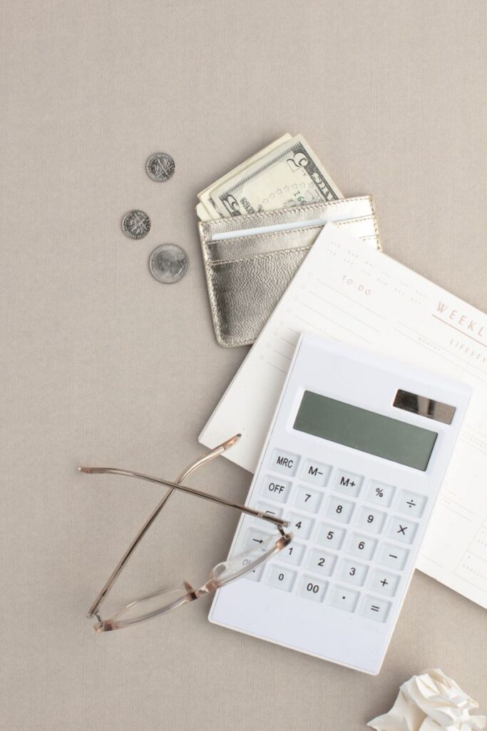 cash, notebook, purse, calculator and glasses on a table
