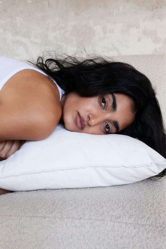 woman with head on pillow looking at camera