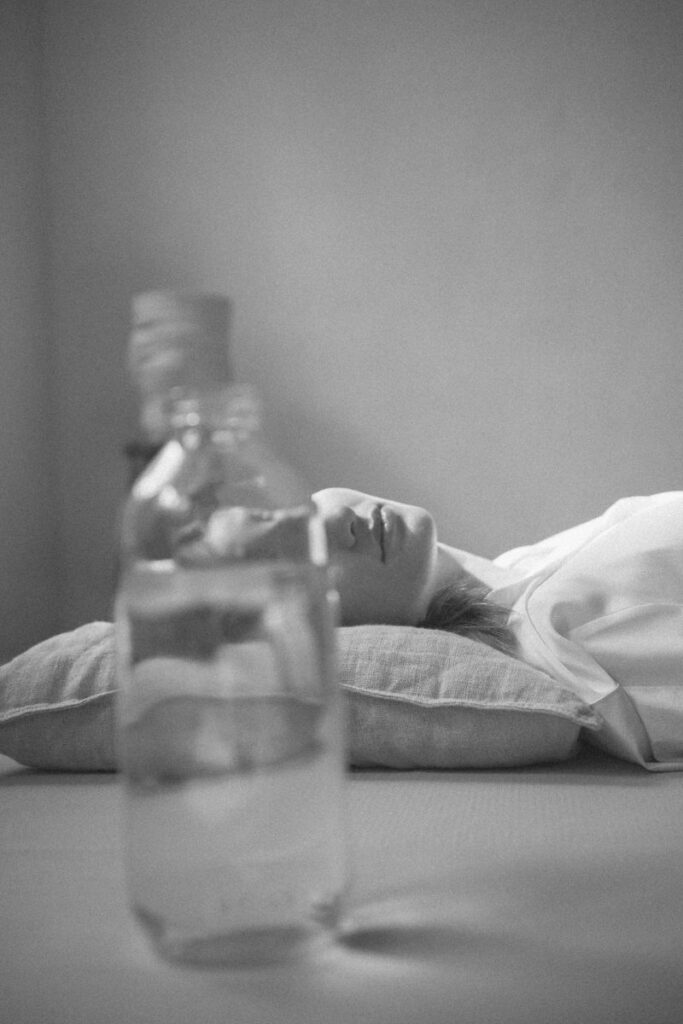 woman lying down with face obscured by bottle of water