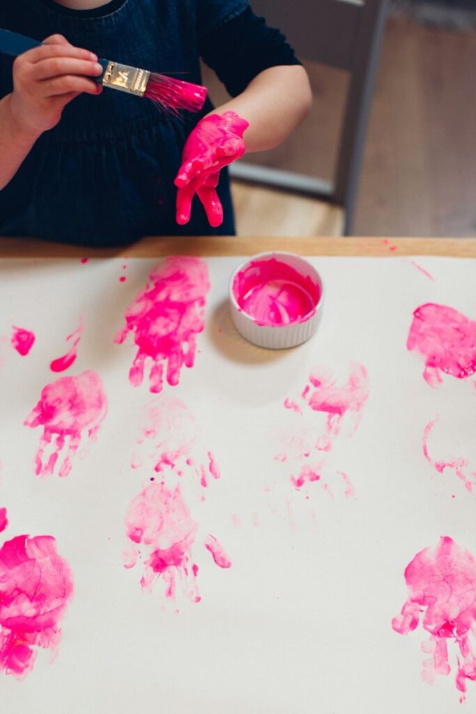 child painting hand pink in mindful workshop